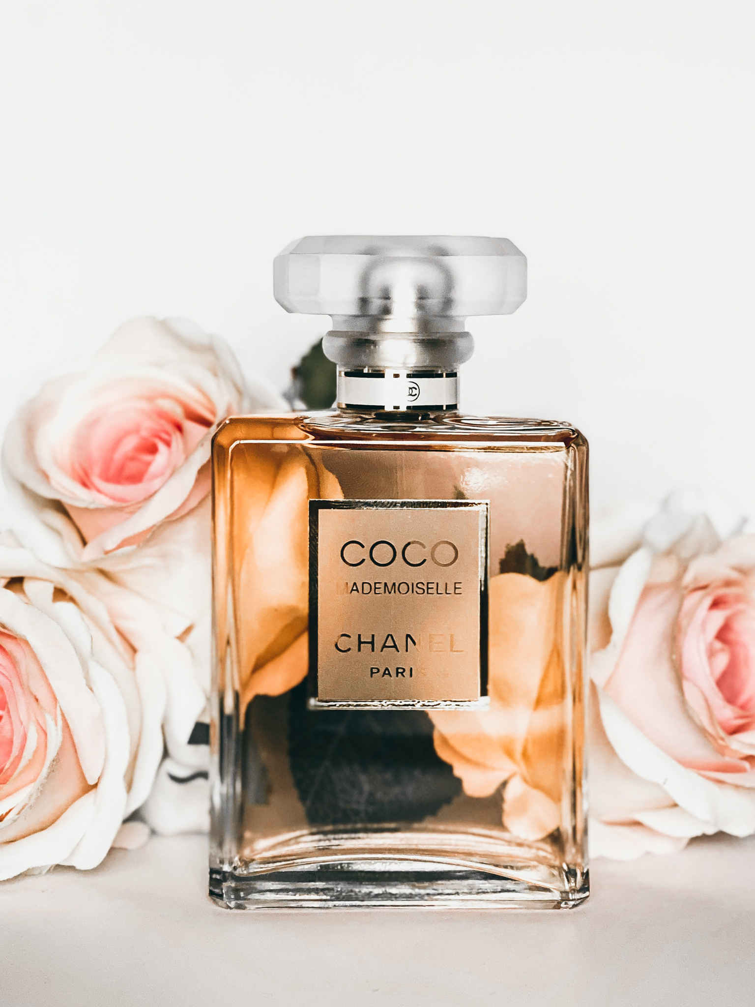 Chanel Coco Mademoiselle perfume bottle styled with soft pink roses, perfect for luxury gifting hampers.