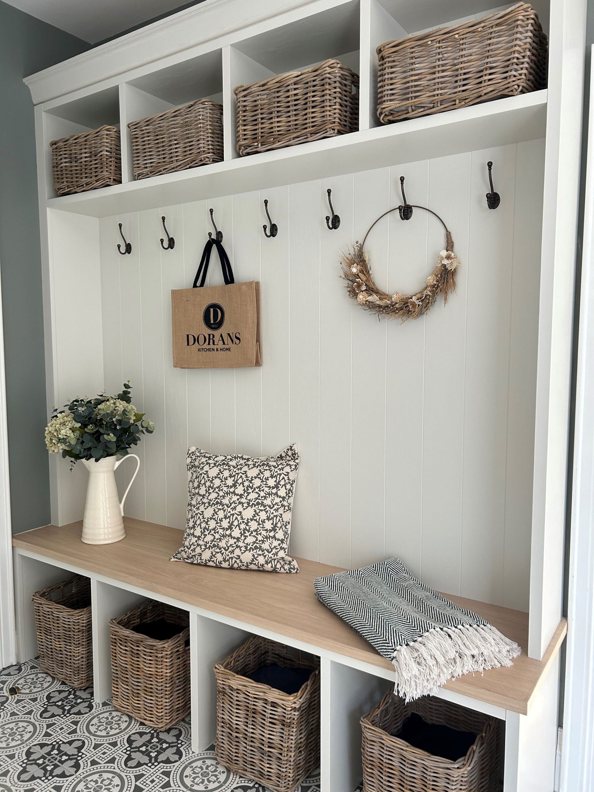 Stylish hallway bench with wicker storage baskets underneath and matching baskets above, perfect for keeping everyday items tidy.