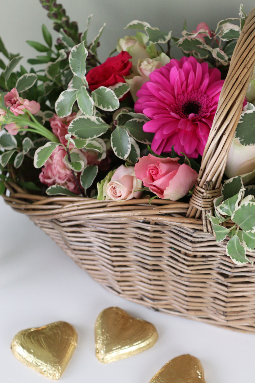 a trug filled with pink flowers and foliage for a mother's day gift