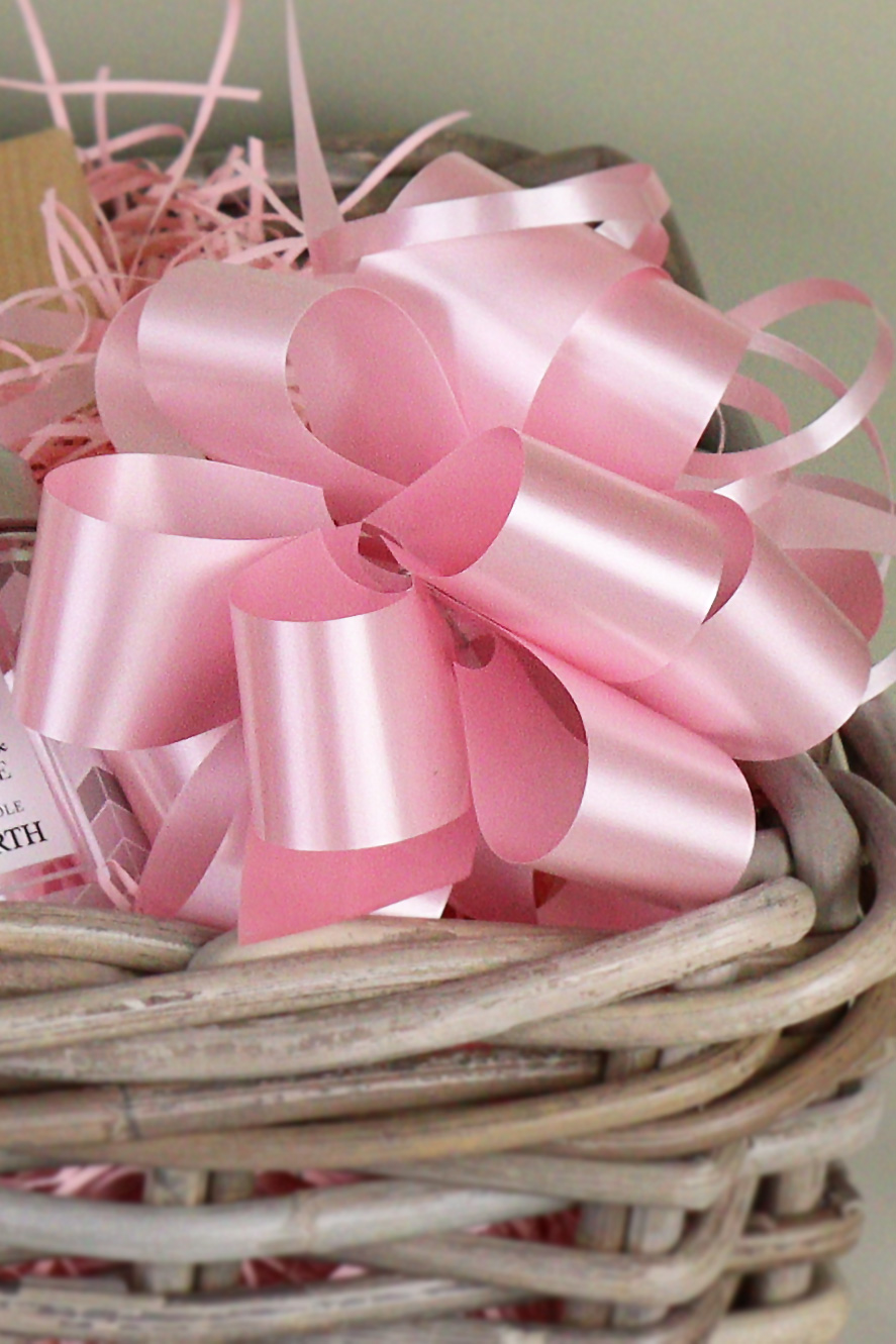 a pink satin bow on a wicker gift basket.