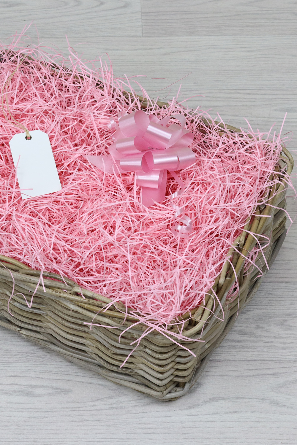 a grey woven hamper with pink bow and shred.