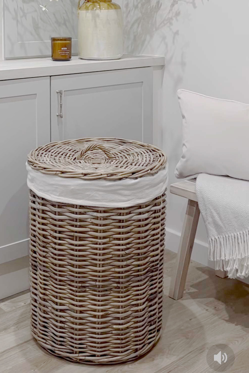 Round rattan laundry basket with fabric liner, ideal for a tidy bedroom or bathroom.