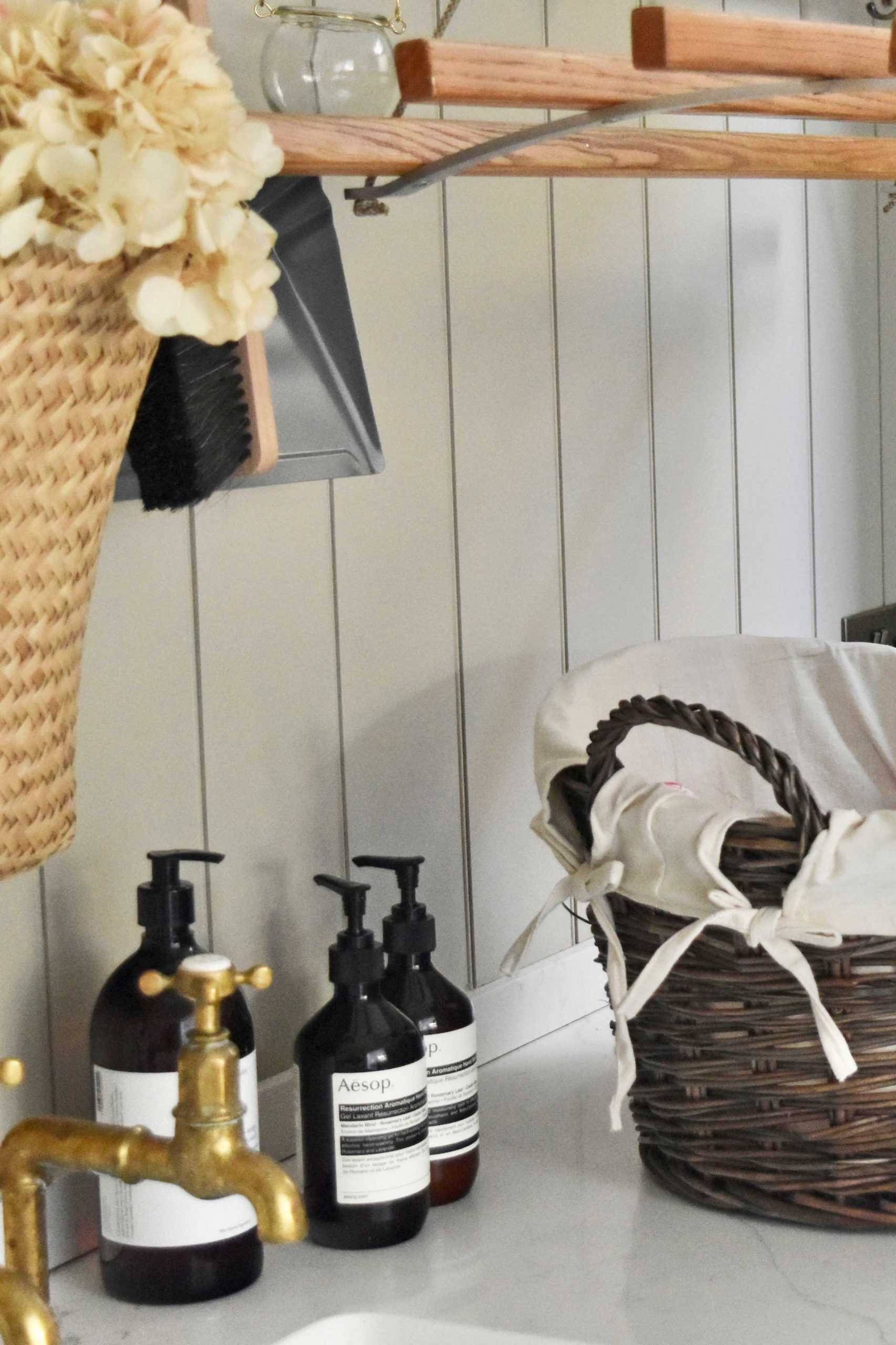 Cleaning products displayed next to an antique wash wicker washing basket styled in a rustic utility room