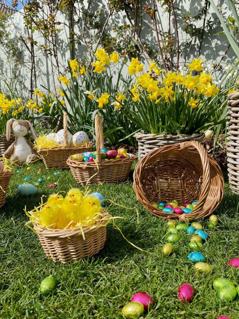 An Easter egg hunt in a garden full of wicker shopping baskets with chocolate eggs.