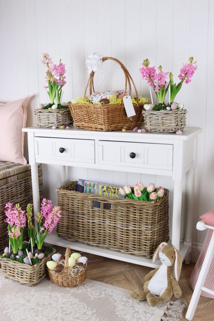 A console table styled for Easter, complete with gift hampers full of chocolate eggs.