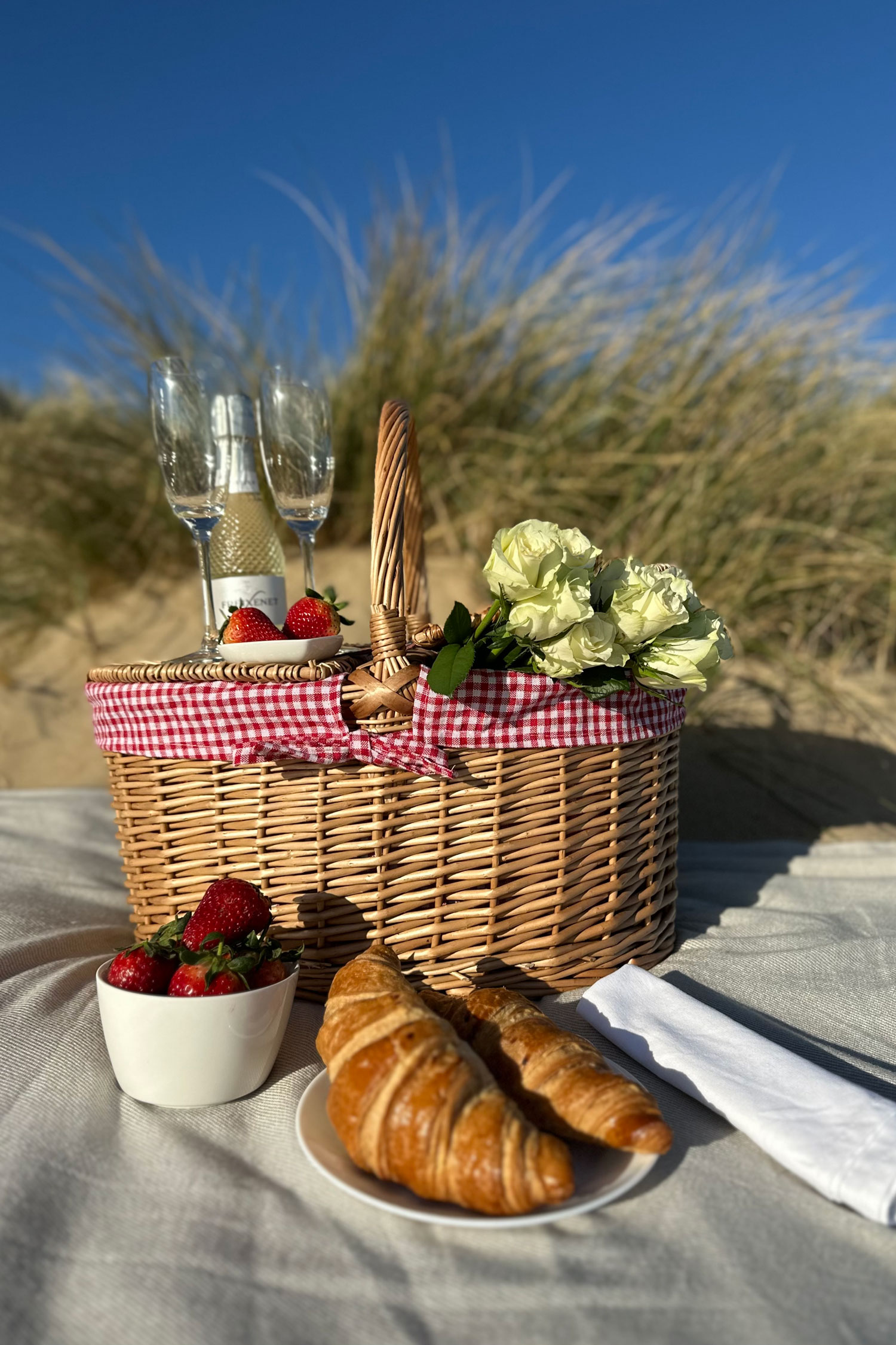 A red check picnic hamper with delicious croissants and strawberries