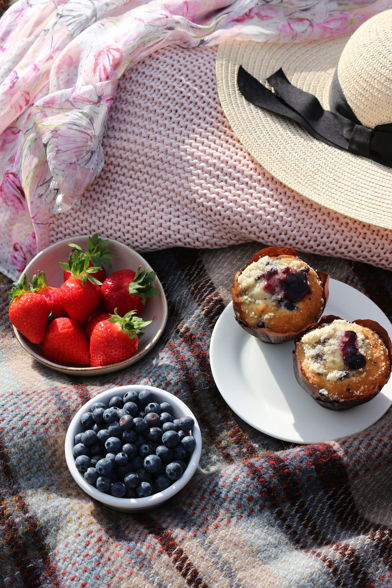 A sweet and indulgent picnic selection including strawberries, blueberries and muffins.