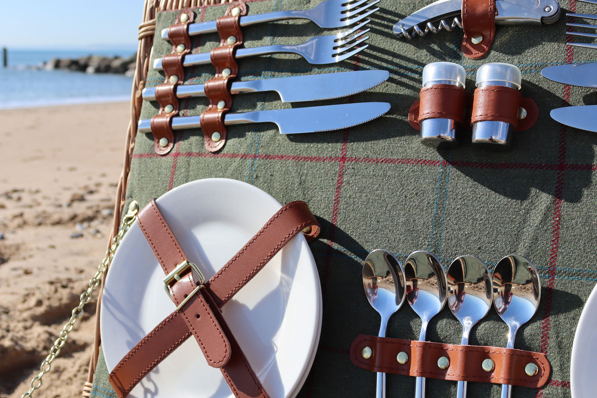 A close up of a picnic hamper showing the selection of cutlery and plates that it offers.
