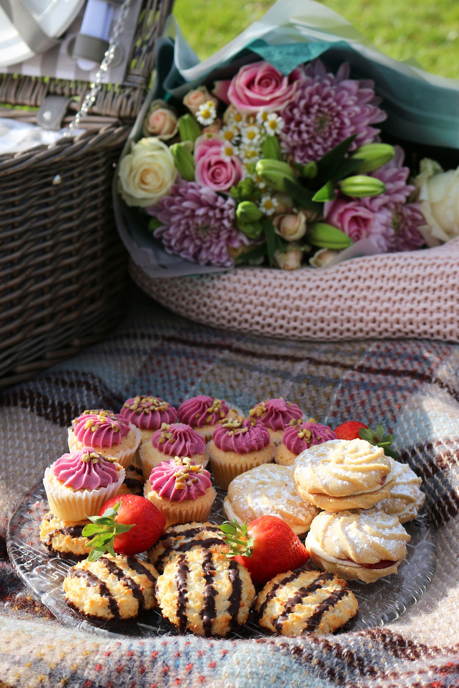 A sweet selection of picnic food such as mini cakes, biscuits and macaroons.