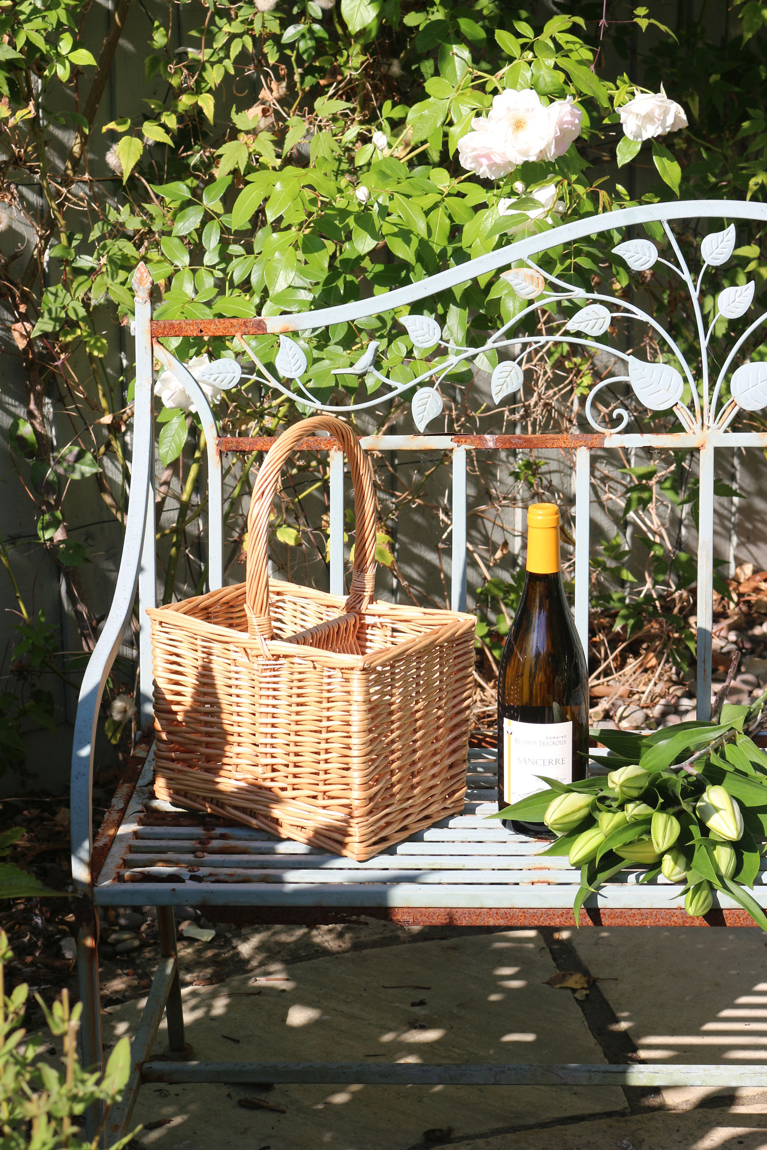A wine basket on a sunny garden bench