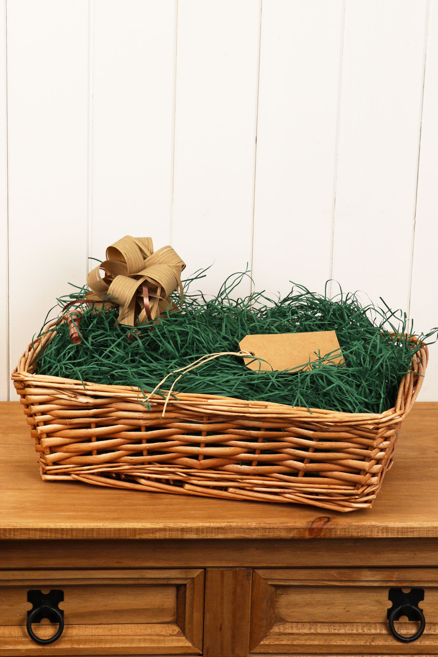 A stunning natural wicker hamper full of green hamper shred