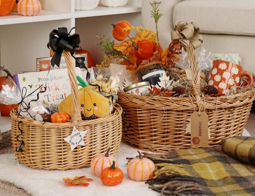 Two wicker Boo Baskets filled with autumn treats, mini pumpkins, and cosy autumn themed goodies on a soft rug.