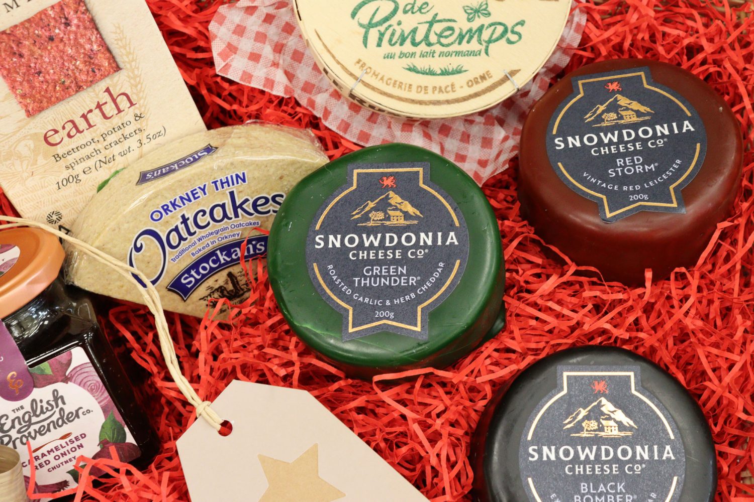 Close-up of artisan cheese hamper featuring Snowdonia truckles, creamy Camembert, oatcakes, and savoury chutney.
