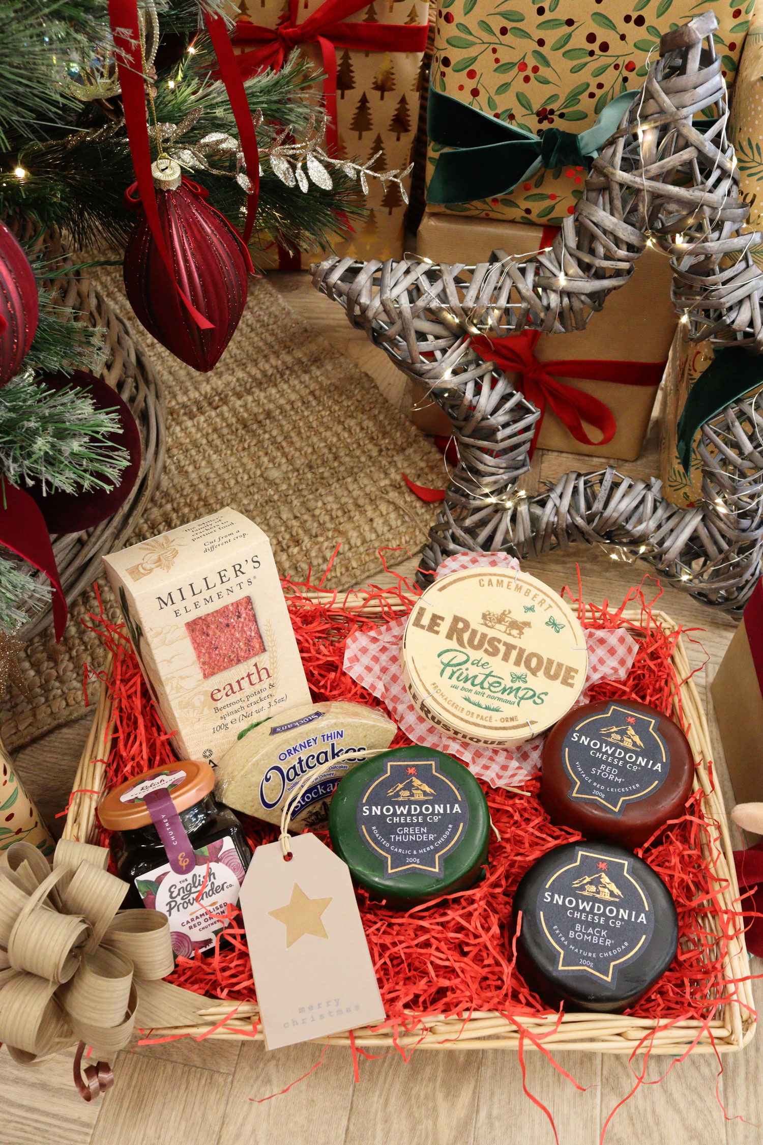 Luxury cheese Christmas hamper with Camembert, Snowdonia cheeses, crackers, and chutney in a wicker tray.