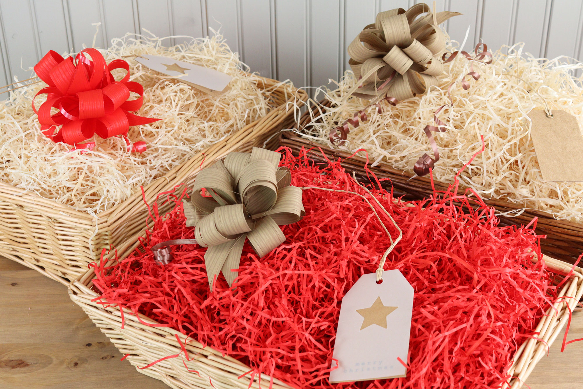 Empty Christmas hampers lined with shredded paper and festive bows, ready to fill with seasonal treats and gifts.