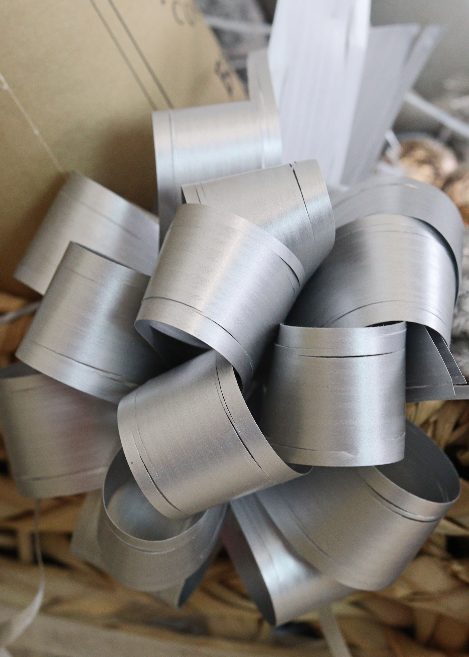 Close-up of a metallic silver ribbon bow attached to a burr basket, adding a festive finishing touch to the gift set.
