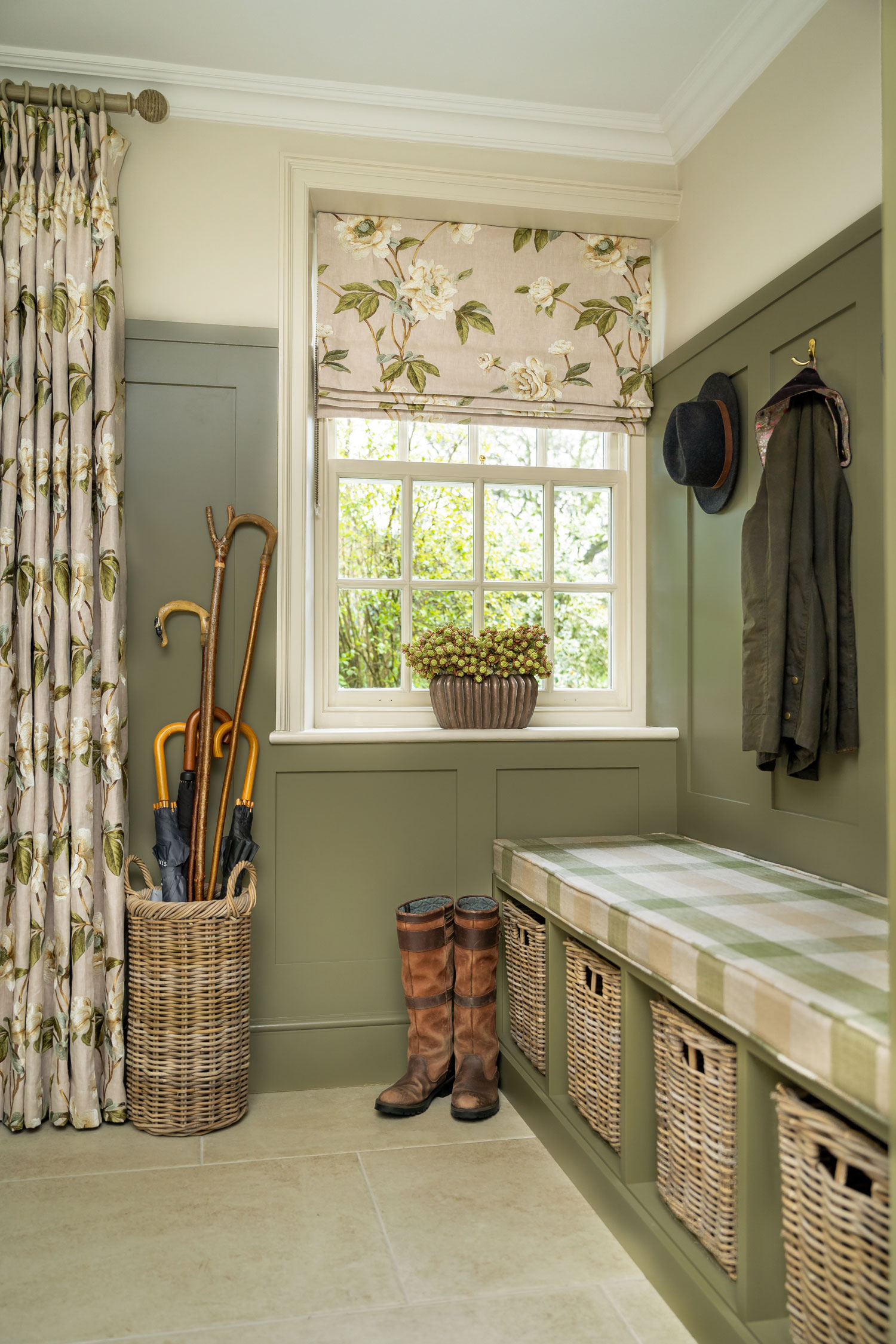 Elegant boot room with a round rattan umbrella basket and cube shoe baskets under a sage bench for tidy, stylish hallway storage.
