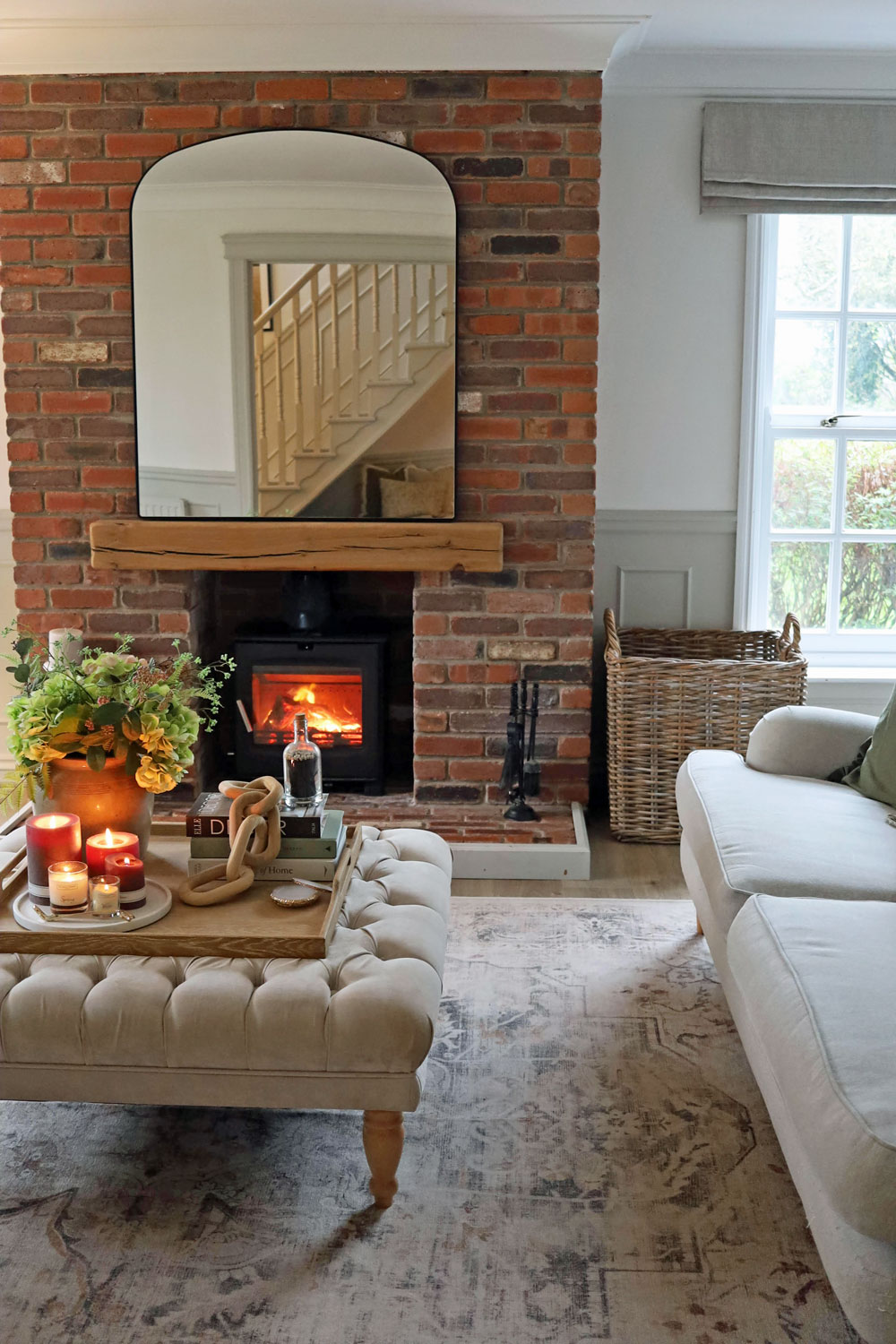 Cosy living room with a roaring log burner and a large rattan log basket beside the hearth, perfect for fireside wood storage.