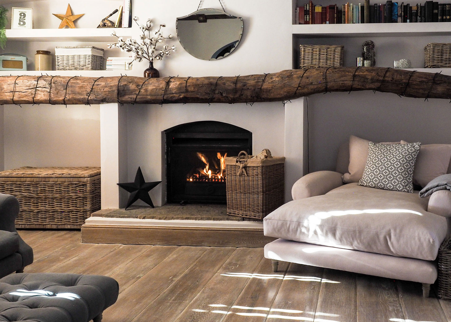 Cosy living room with a roaring fireplace, styled with a rustic wicker log basket.