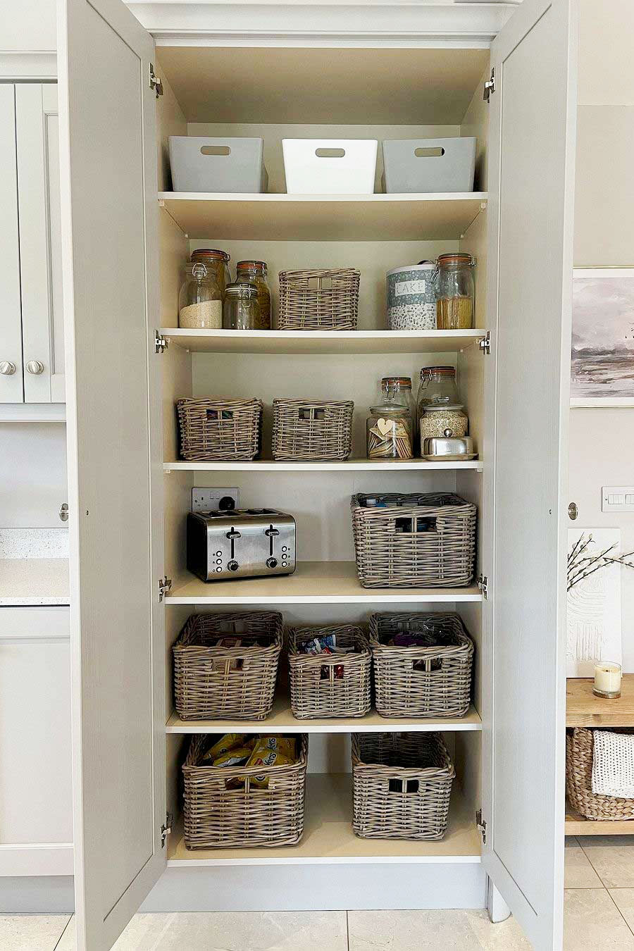 Tall white pantry cupboard filled with grey & buff rectangular storage baskets for chic and space-saving kitchen organisation.