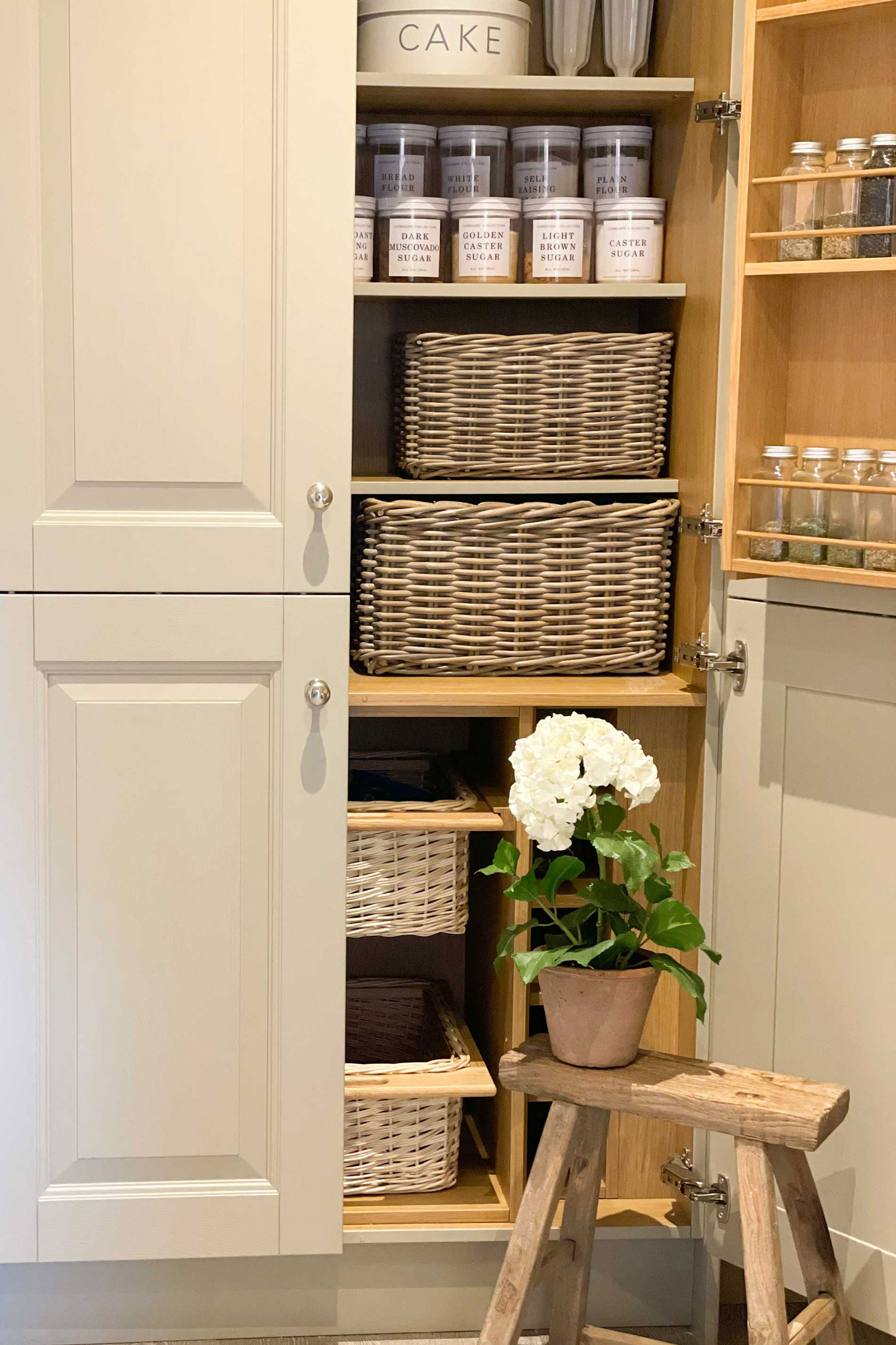 Stylish kitchen cabinet with stacked rattan storage baskets, ideal for decluttering baking supplies and everyday kitchen essentials.