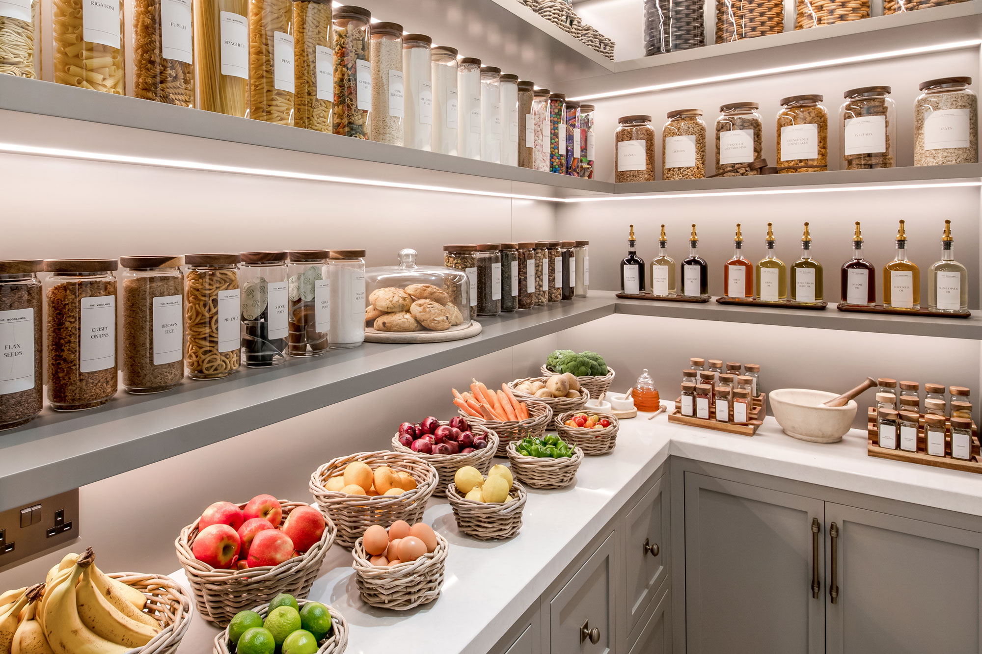 A beautifully styled pantry with grey & buff rattan round storage baskets holding fresh fruit and veg, perfect for rustic kitchen organisation.