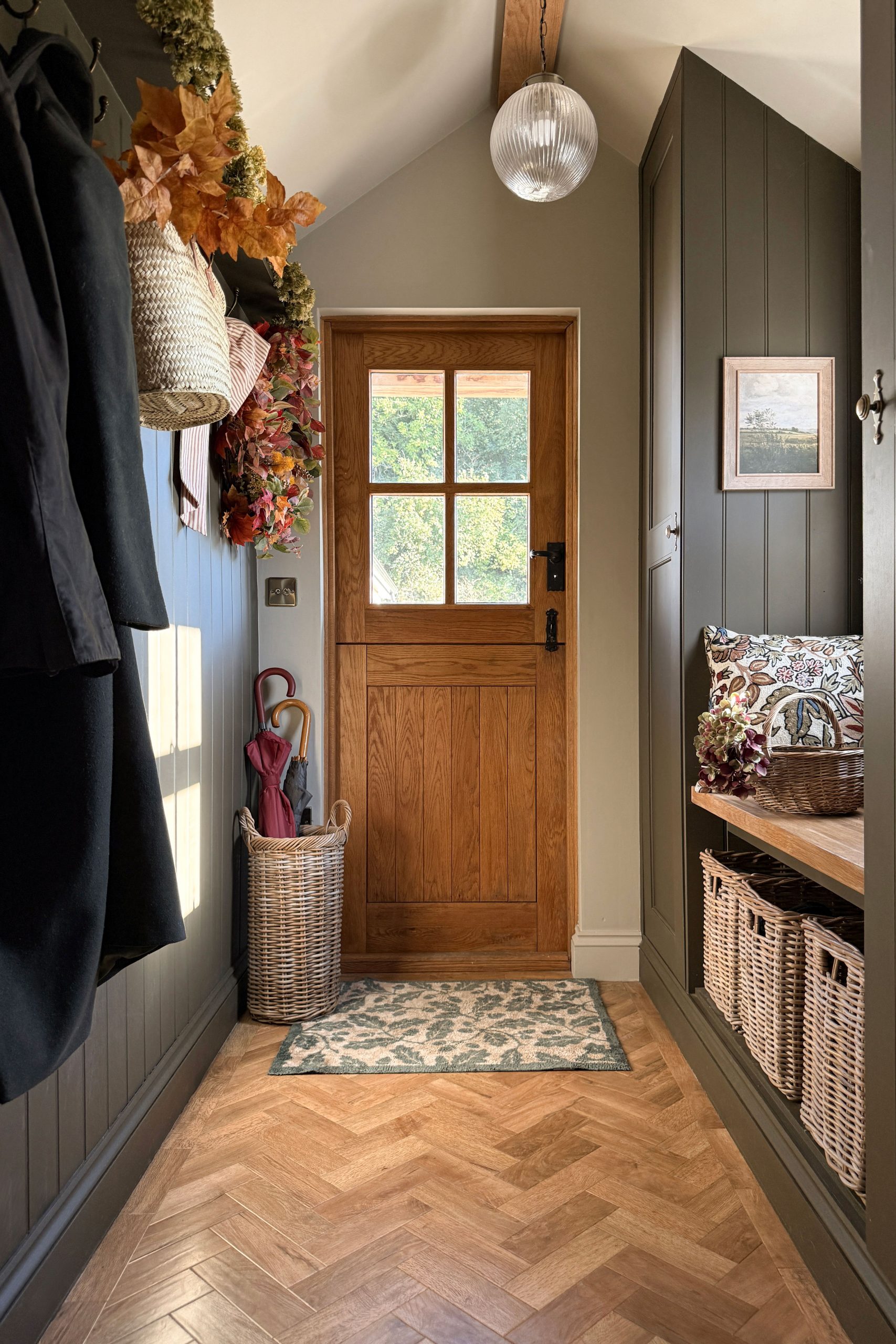 Grey & buff rattan umbrella basket beside a wooden front door, perfect for storing walking sticks and umbrellas in the hallway.