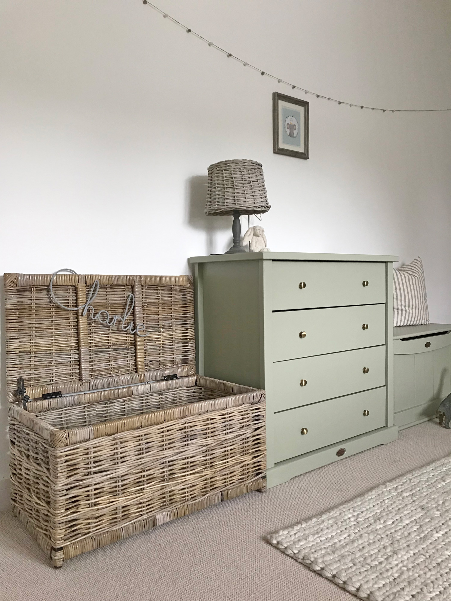 Children’s bedroom with a large rattan storage trunk beside a green chest of drawers, ideal as a stylish toy basket solution.