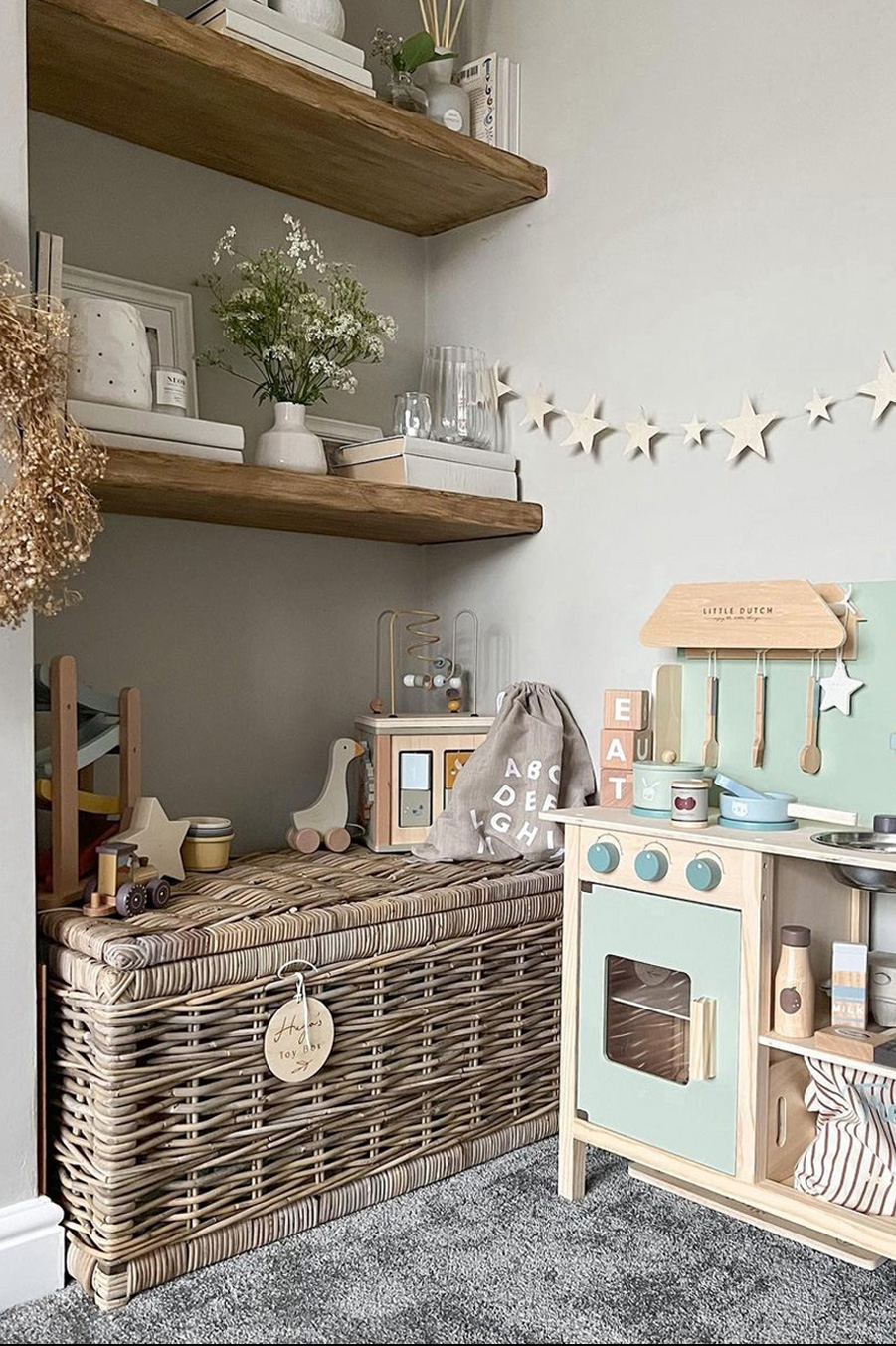 Playroom corner featuring a rattan toy trunk beneath open shelves, perfect for hiding away toys while adding rustic charm.