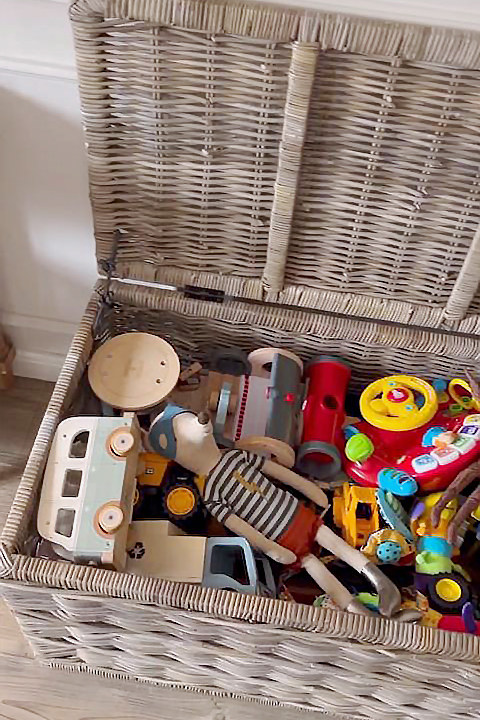 Open rattan storage trunk filled with colourful wooden toys, perfect for keeping a playroom tidy and toys within easy reach.