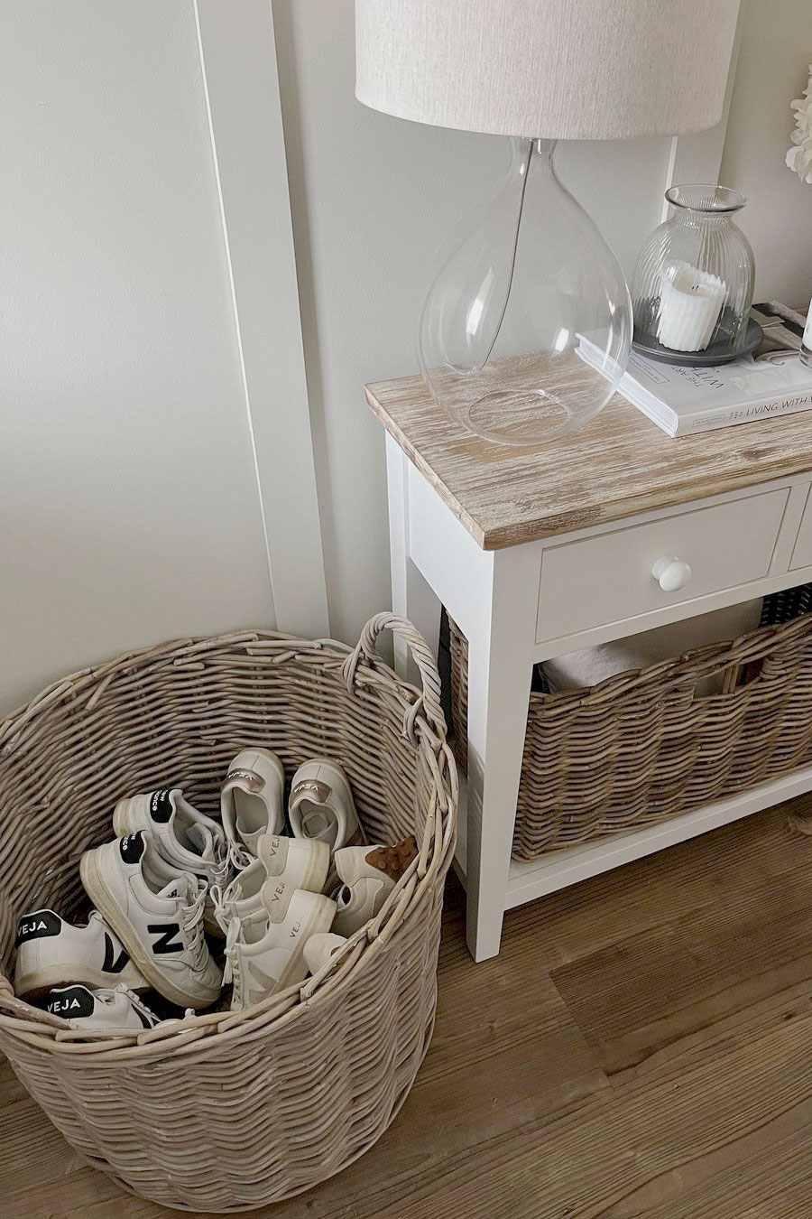 Woven rattan shoe storage basket beside a console table, providing neat, accessible shoe storage with a relaxed look.