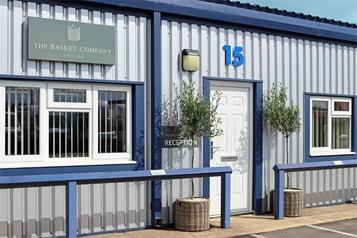 The Basket Company headquarters exterior with blue trim, wicker planters and white reception door